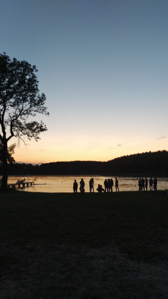 Sil­hou­et­te einiger Menschen abends am See